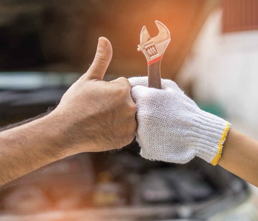 Mechanic hand checking and fixing a broken car in  garage.hand of mechanic with thumbs up and tool